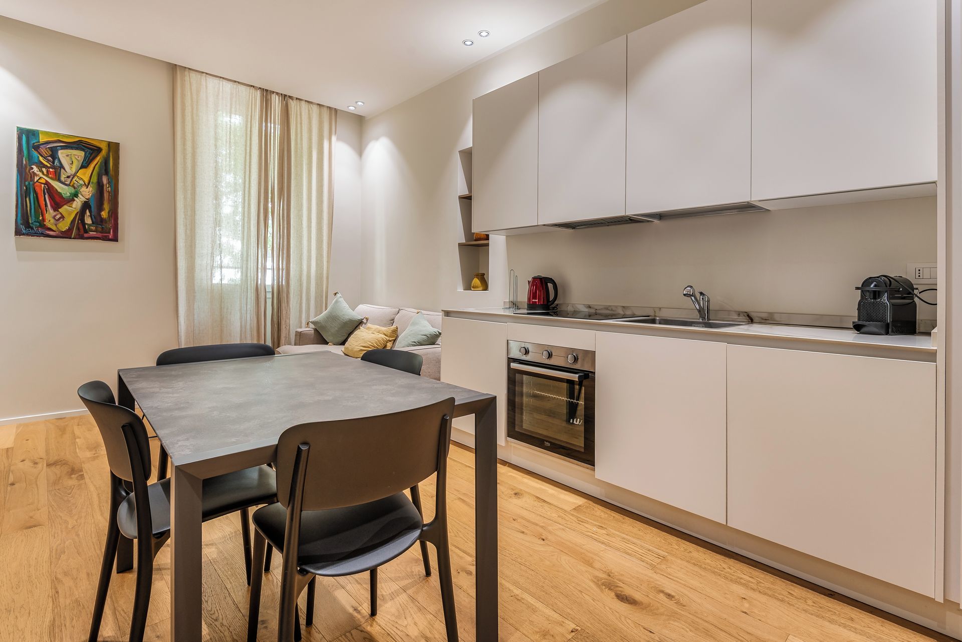 Eine moderne Küche mit eingebautem Backofen, einem Esstisch mit Stühlen und einem Fenster mit Vorhängen.