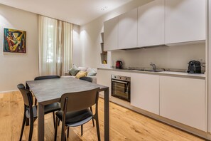 Eine moderne Küche mit eingebautem Backofen, einem Esstisch mit Stühlen und einem Fenster mit Vorhängen.