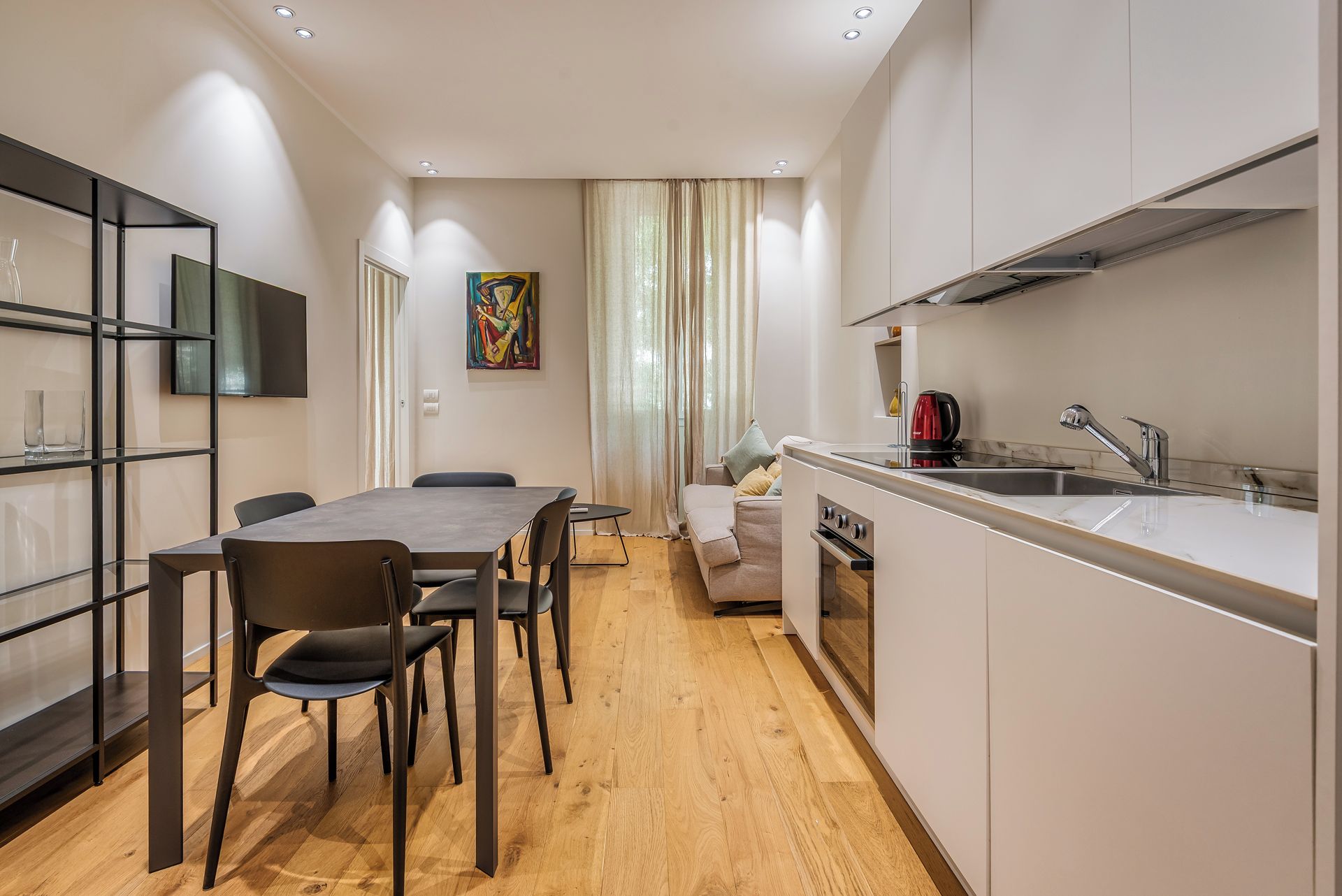 Een moderne keuken met een eethoek, houten vloeren en een bank.