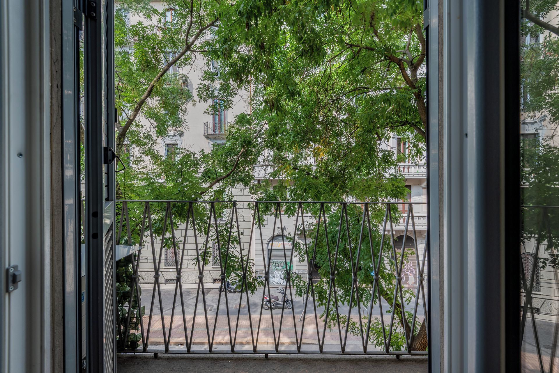 Une vue à travers une grille métallique, avec une rue et des bâtiments en arrière-plan.