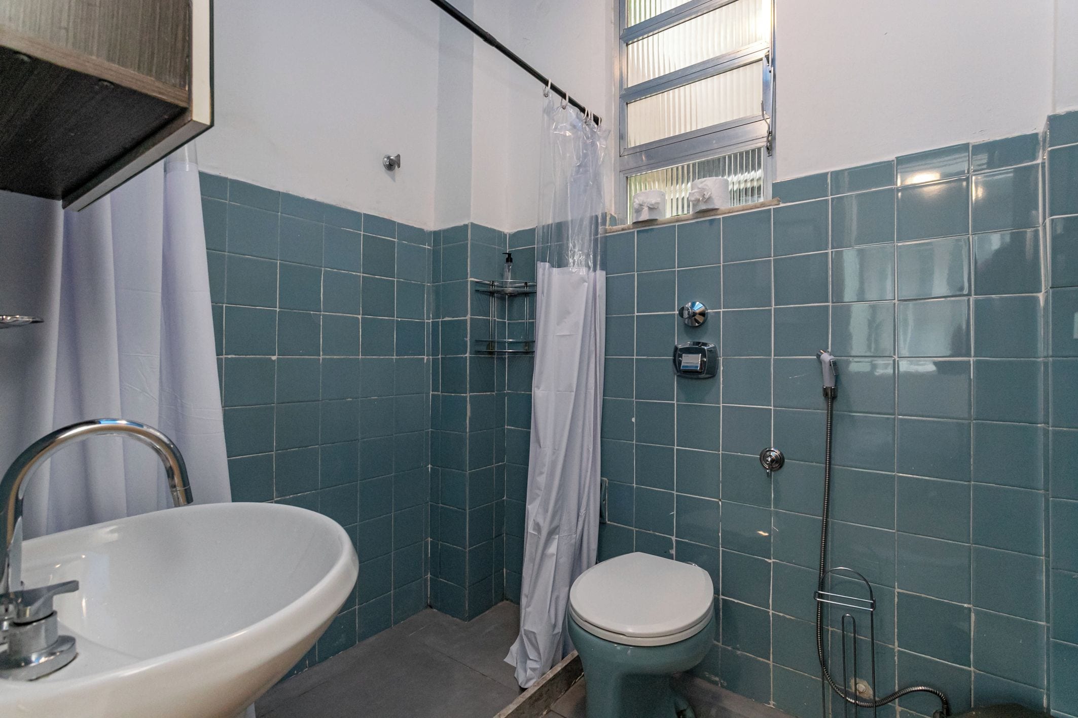 Une salle de bain équipée d’un lavabo, de toilettes, d’une douche et d’une fenêtre donnant sur un beau paysage.