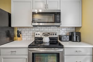 Une cuisine équipée d’un four à micro-ondes, d’une cuisinière, d’un four, d’un grille-pain et d’une machine à café.
