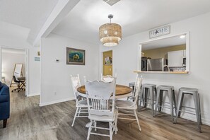 Un coin repas avec une table ronde, des chaises blanches et un luminaire suspendu.