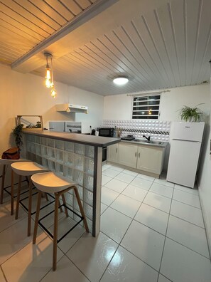 Eine Küche mit Bar, weißen Schränken, einer Mikrowelle und einem Kühlschrank.