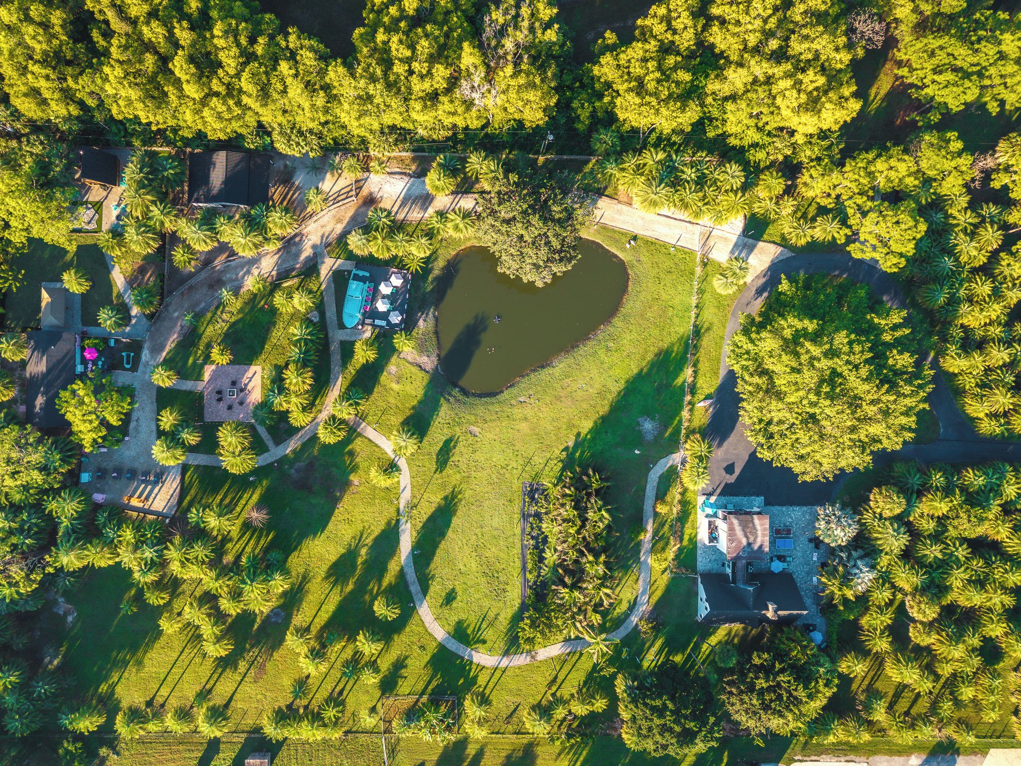 Eine Vogelperspektive eines Parks mit Teich, Wegen und Gebäuden.