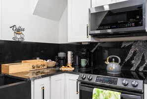 A modern kitchen with a coffee-themed wall decal, a Keurig coffee maker, a kettle, and a wooden box labeled 'But First Coffee.' - Farm Stay, 5beds / 4.5 baths, Palm Tree, Alpaca & Llama Farm, 5 Acres (West Palm Beach)