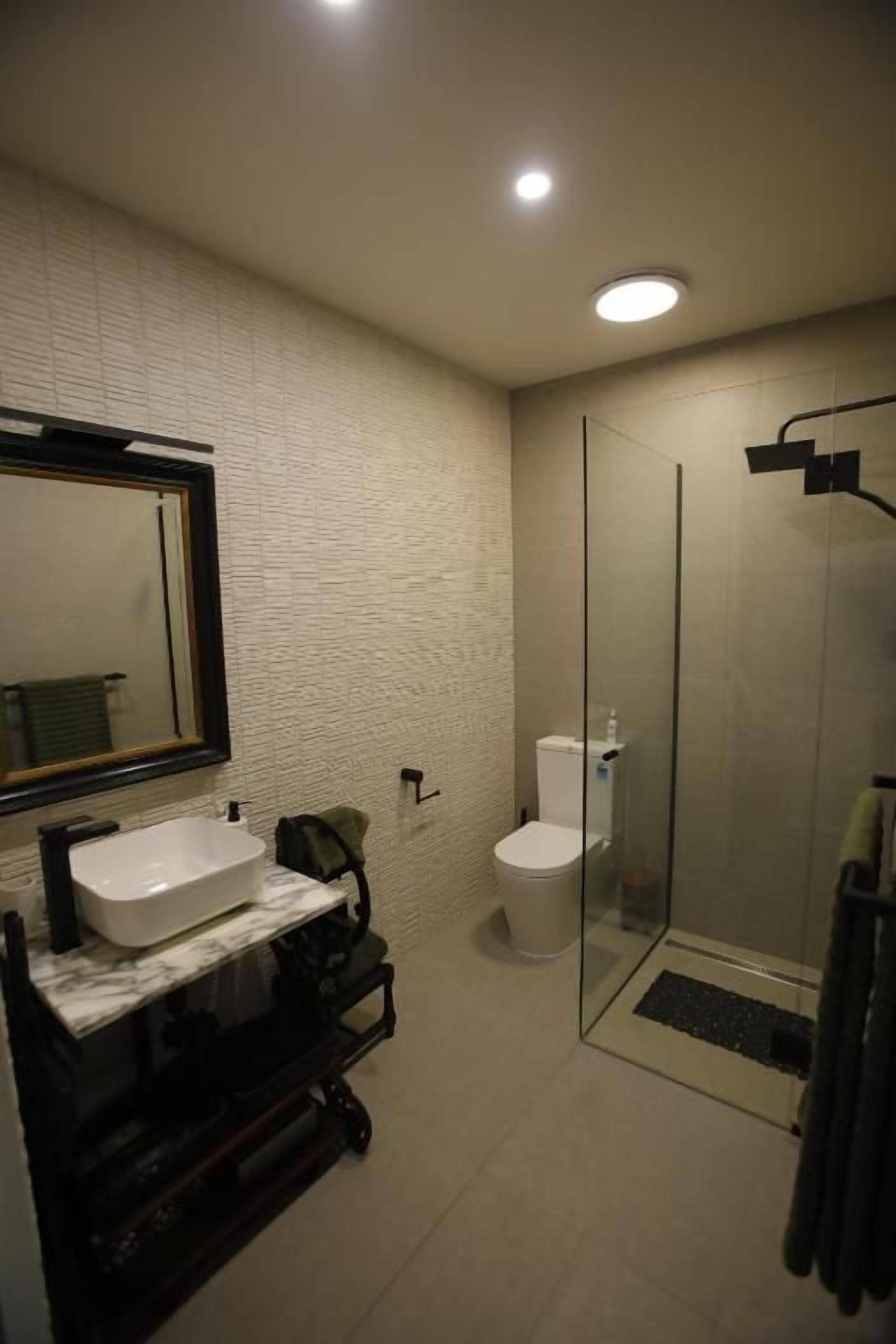 Un baño con lavamanos de mármol, inodoro y ducha con cerramiento de vidrio.