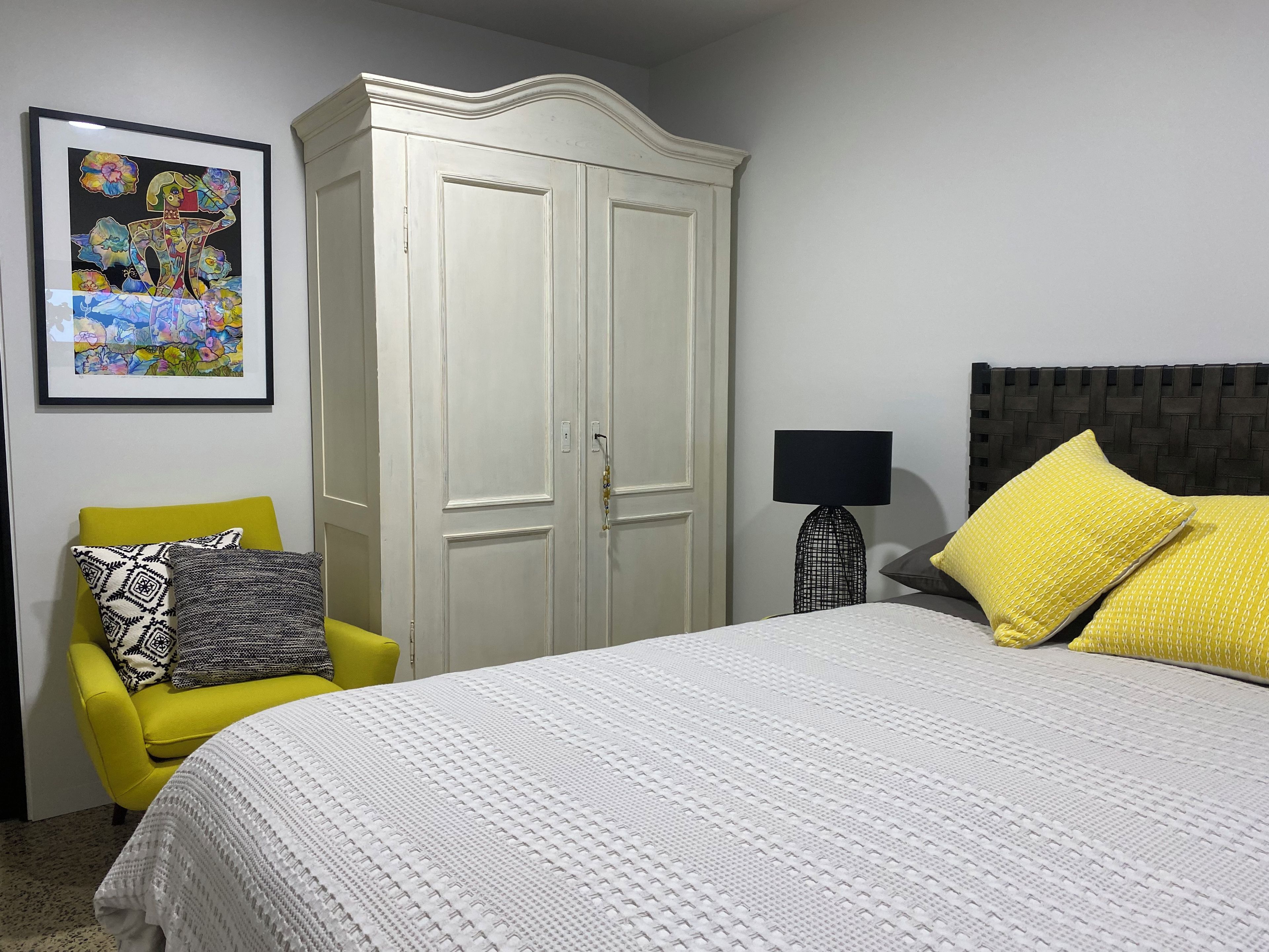 A bedroom with a bed, a wardrobe, a chair, and a lamp.