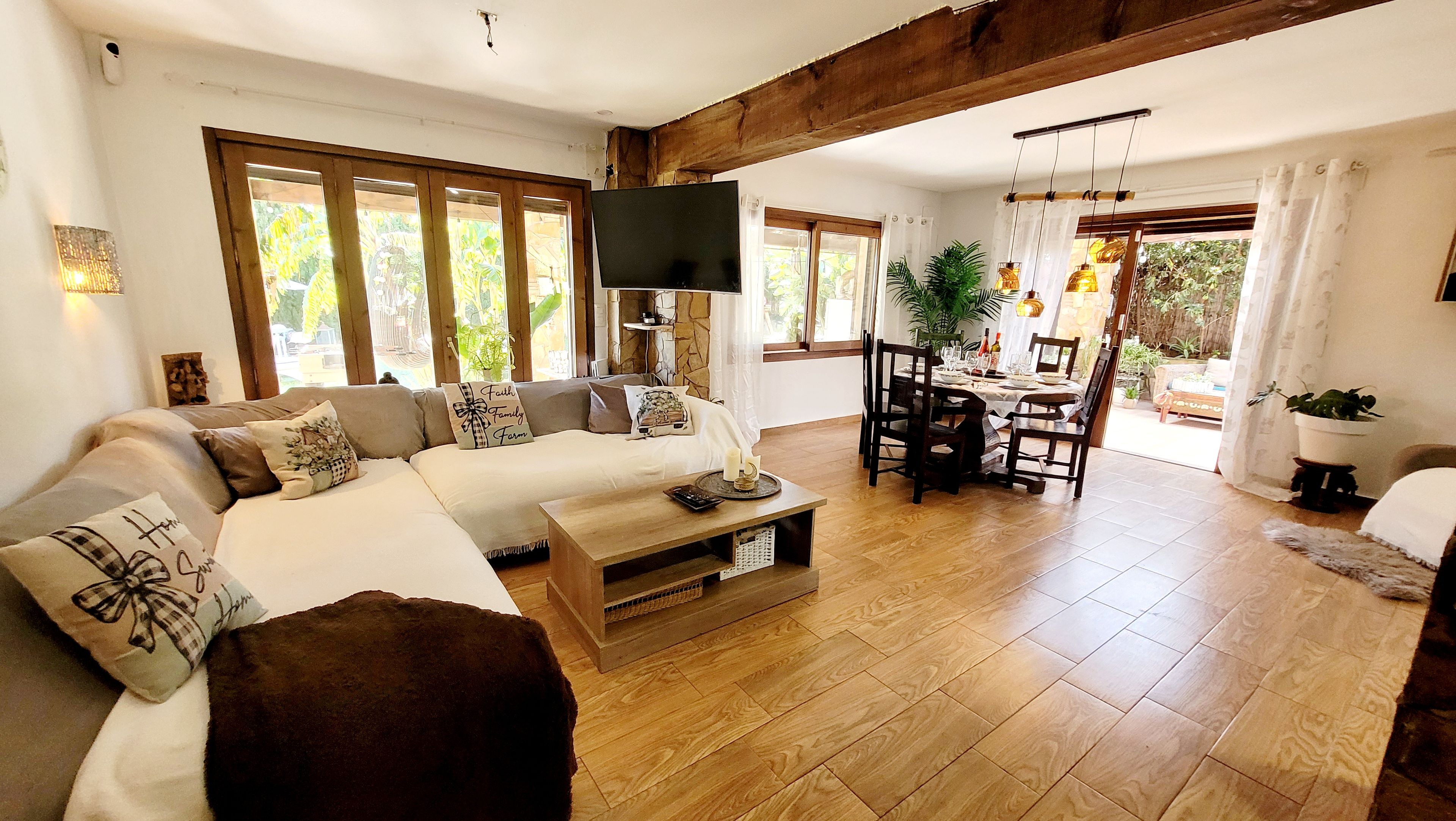 A spacious living room with a large sofa, a coffee table, and a dining area with chairs and a table set for a meal.