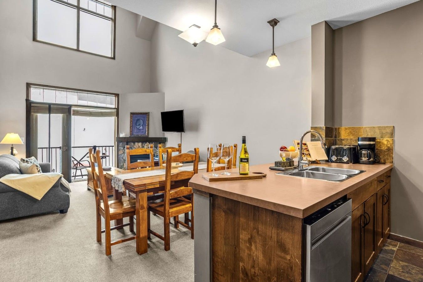 Une cuisine moderne avec un îlot central en bois, un coin repas avec des chaises, un téléviseur à écran plat et une cheminée en pierre.