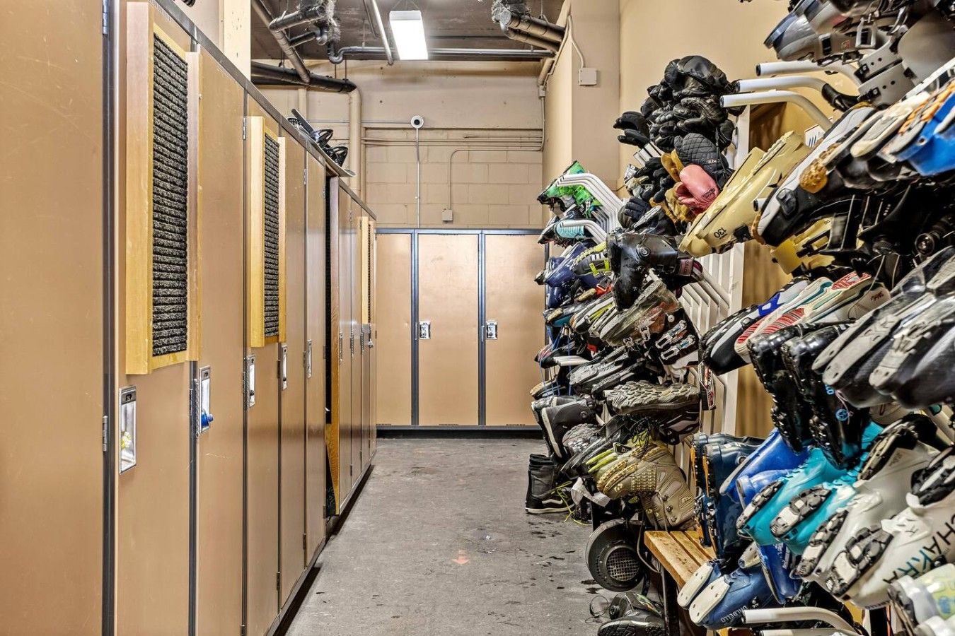 Un couloir étroit, avec des casiers d’un côté et, de l’autre, un mur où sont empilés des casques et des équipements de moto.