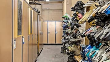 Un couloir étroit, avec des casiers d’un côté et, de l’autre, un mur où sont empilés des casques et des équipements de moto.