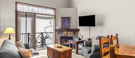 Ein Wohnzimmer mit Kamin, Fernseher, Sofa, Couchtisch und Esstisch.