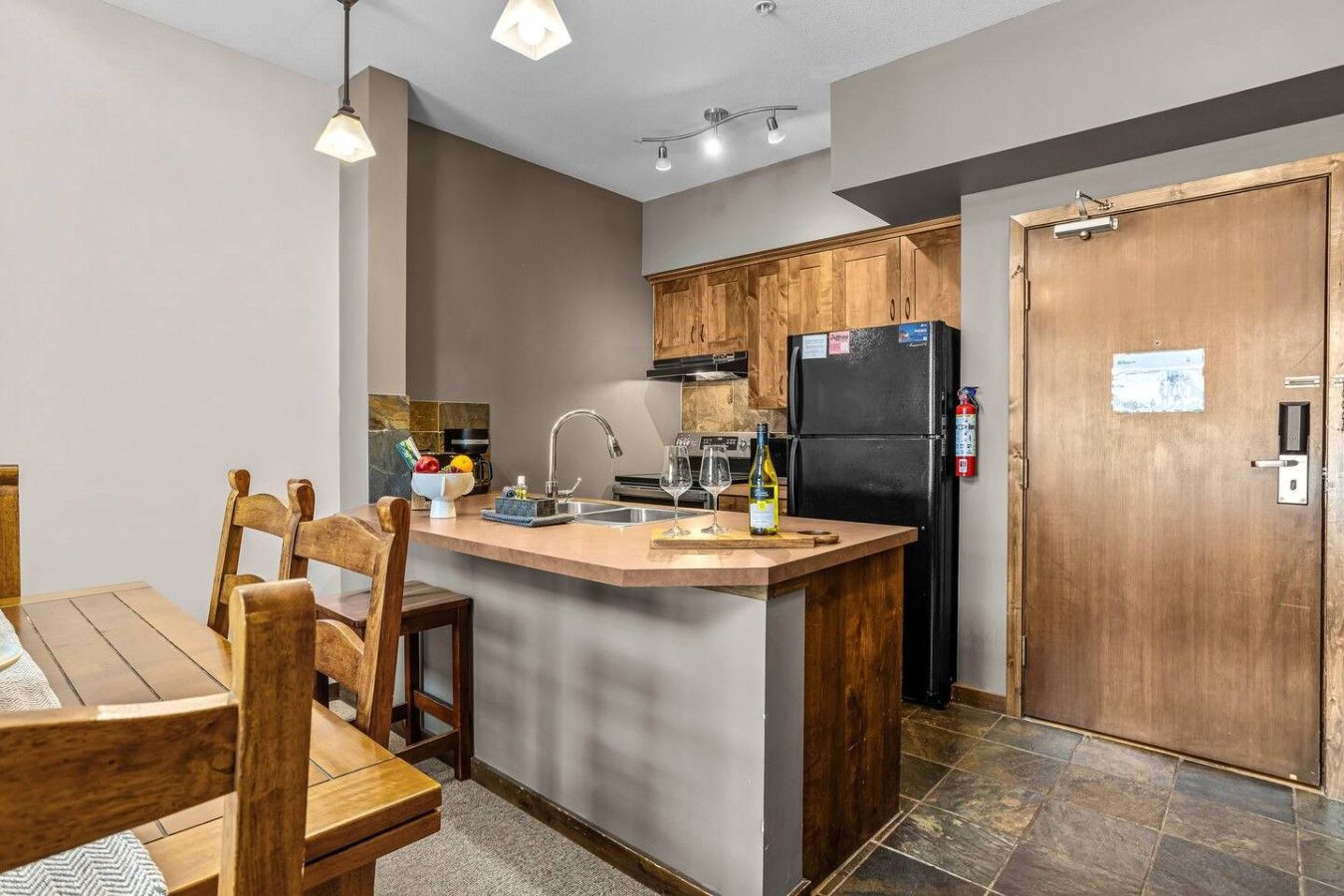 A modern kitchen with wooden cabinets, a built-in island, and a black refrigerator.