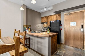 Una cocina moderna con armarios de madera, una isla integrada y un refrigerador negro.