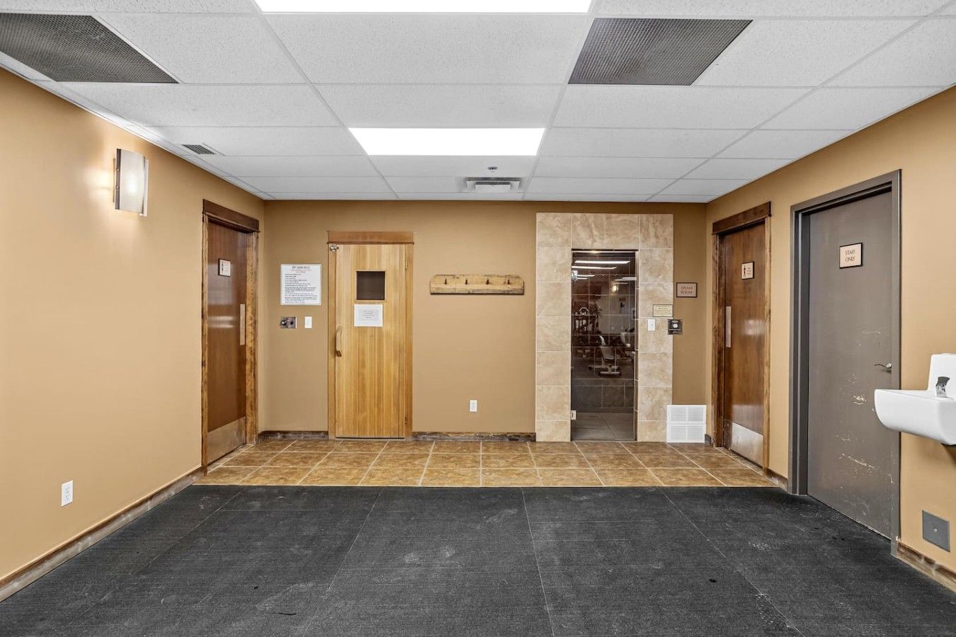 A hallway with a wooden door, a sign, and a restroom door with a sign.