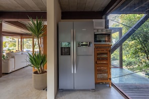 A modern kitchen with a built-in refrigerator, a microwave, and a wooden cabinet. - Residencial Cambaquara 4 (Ilhabela)