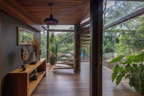 Una scala in legno conduce a un balcone con vista su un giardino rigoglioso.