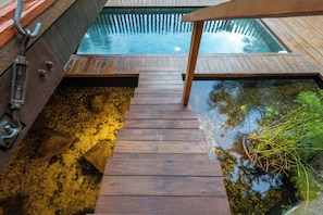 A wooden staircase leading to a pool with a wooden deck and a metal railing. - Residencial Cambaquara 4 (Ilhabela)
