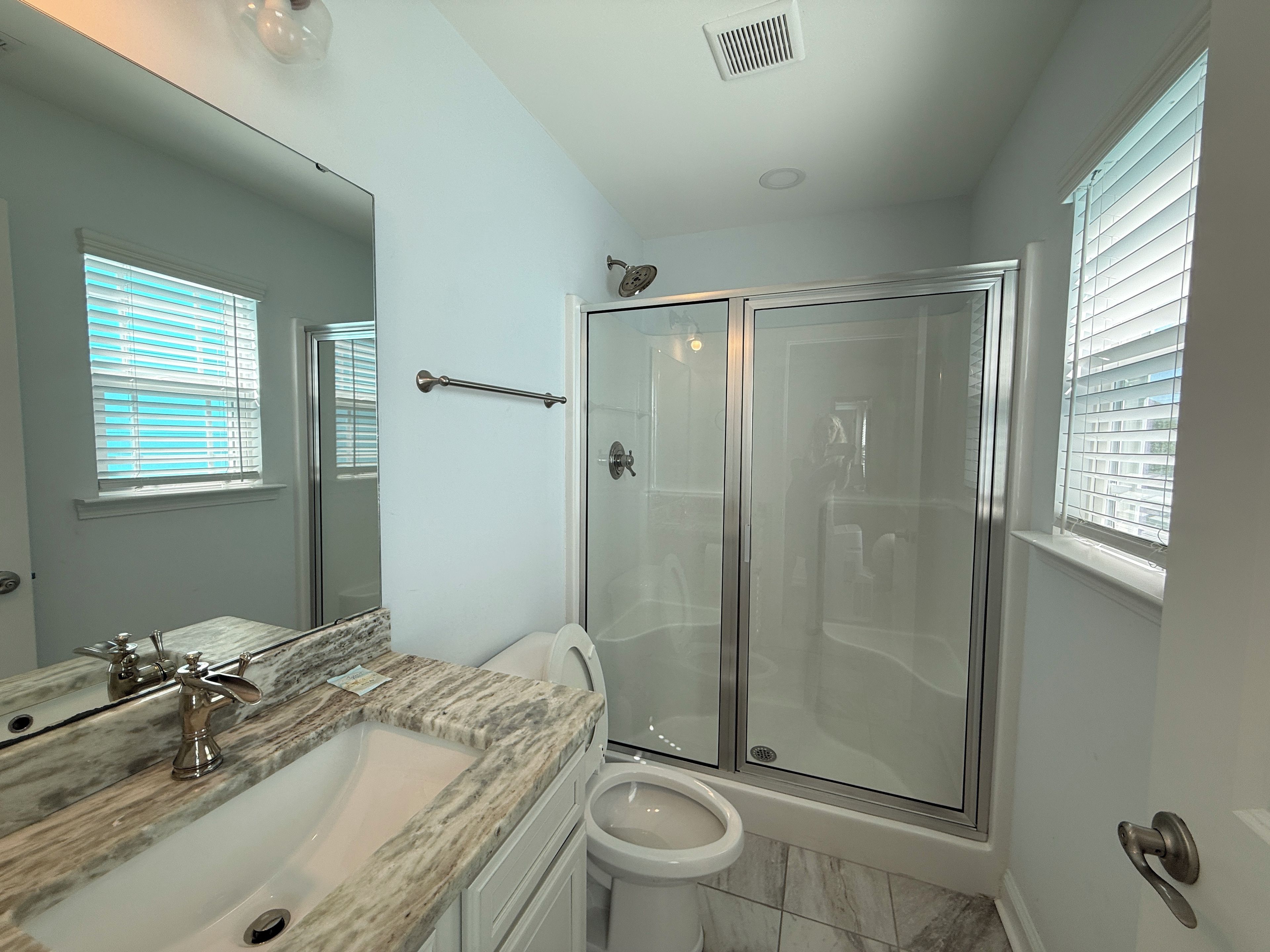 A bathroom with a shower, toilet, and sink.