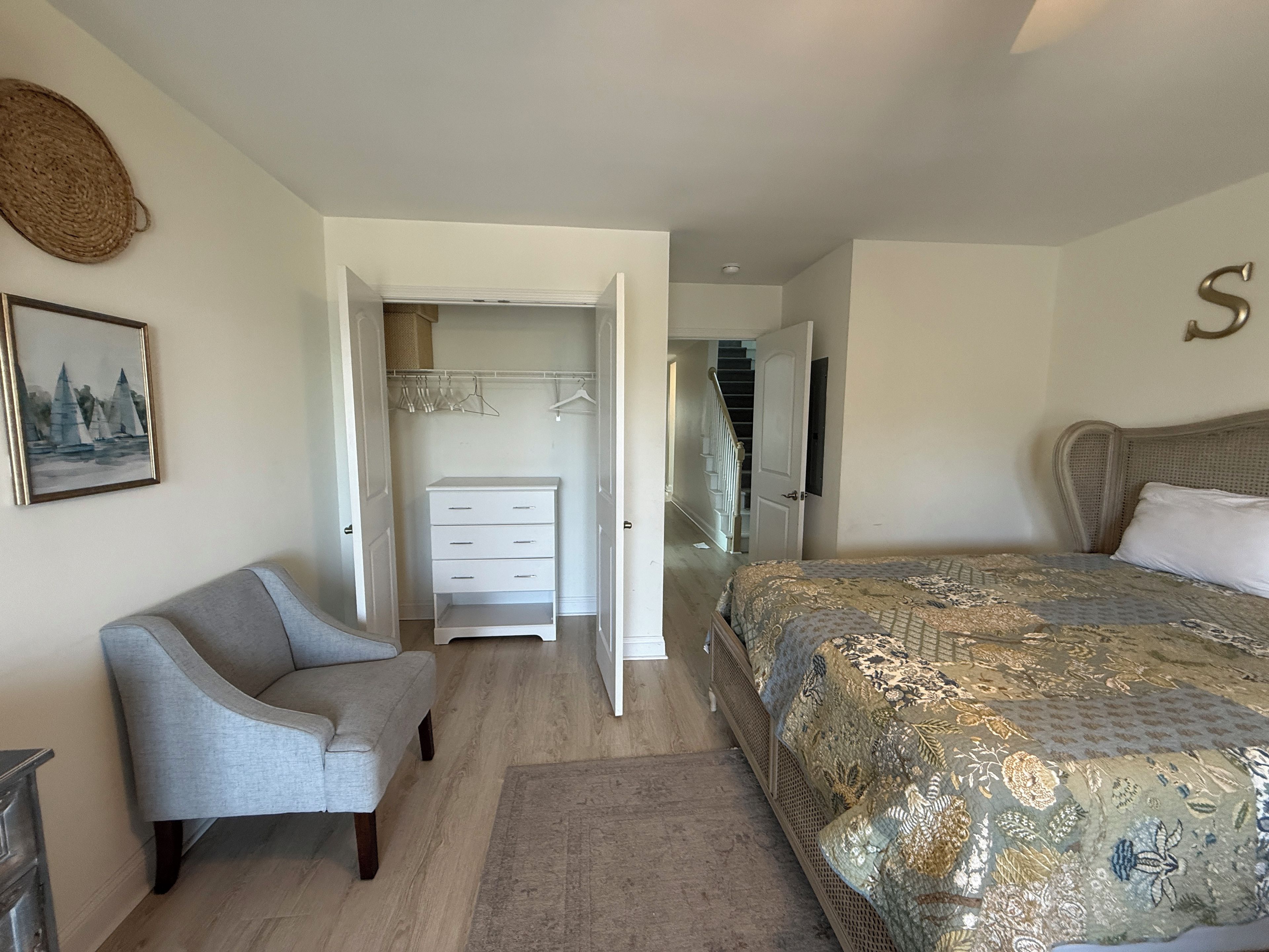 A bedroom with a bed, a chair, a wardrobe, and a staircase.