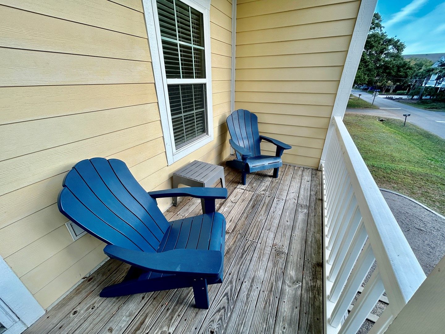A porch with two Adirondack chairs and a small table.