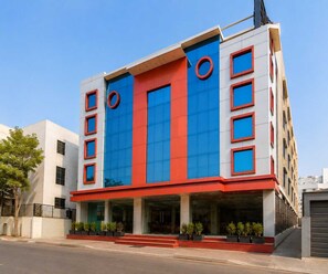 Ein mehrstöckiges Gebäude mit modernem Design, das eine Kombination aus roten und blauen Paneelen an der Fassade zeigt.
