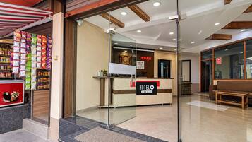 A hotel reception area with a reception desk, a sign indicating 'HOTELO' and 'OYO-Serviced', and a wall with a 'WELCOME' sign.