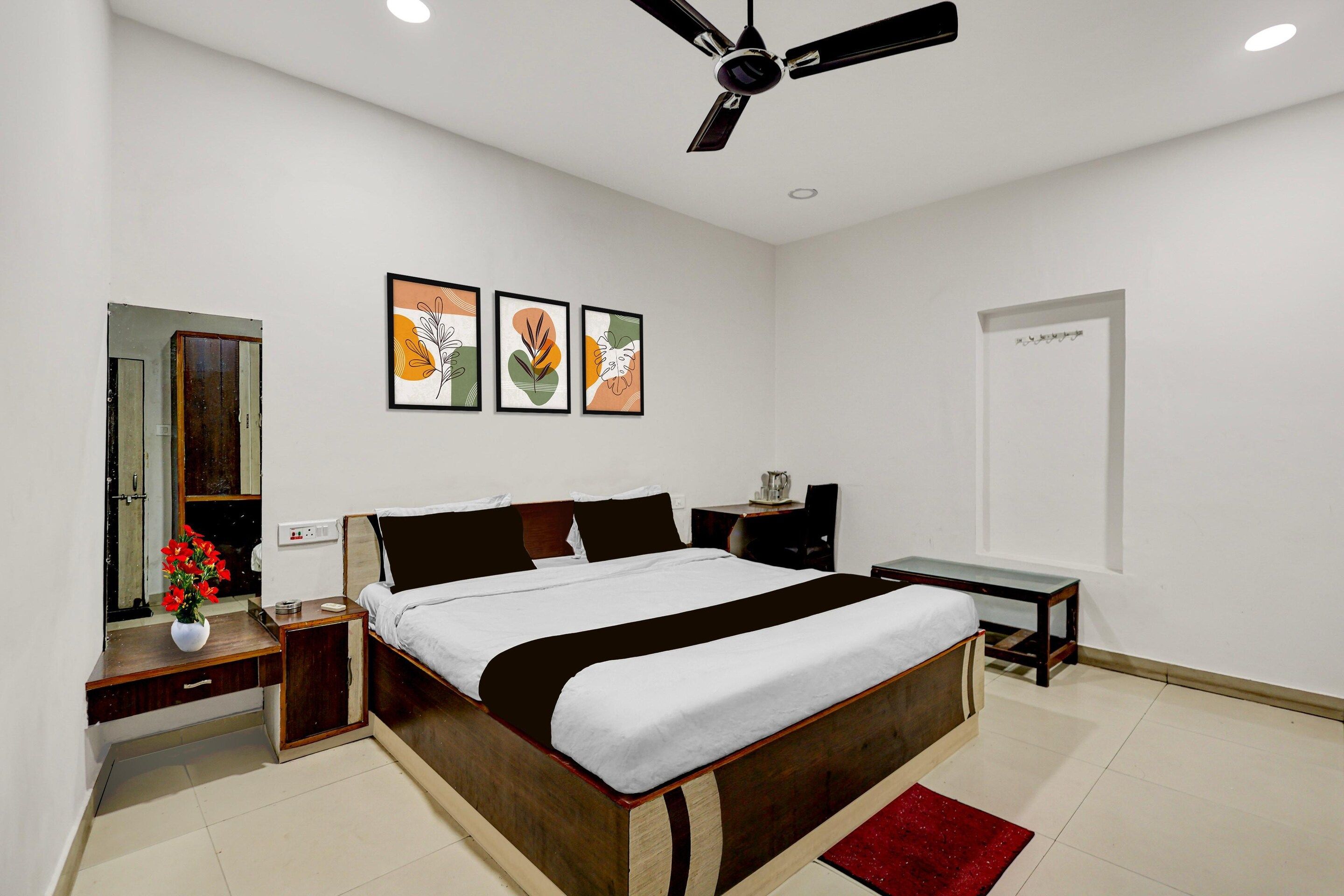 A modern bedroom with a bed, bedside tables, a desk, a ceiling fan, and wall art.