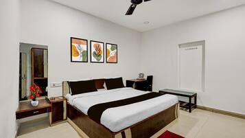 A modern bedroom with a bed, bedside tables, a desk, a ceiling fan, and wall art.