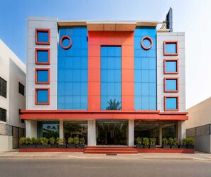 A modern building with a flat facade, large windows, and a red and blue color scheme. - Deluxe Room Hotel Natraj (Raipur)