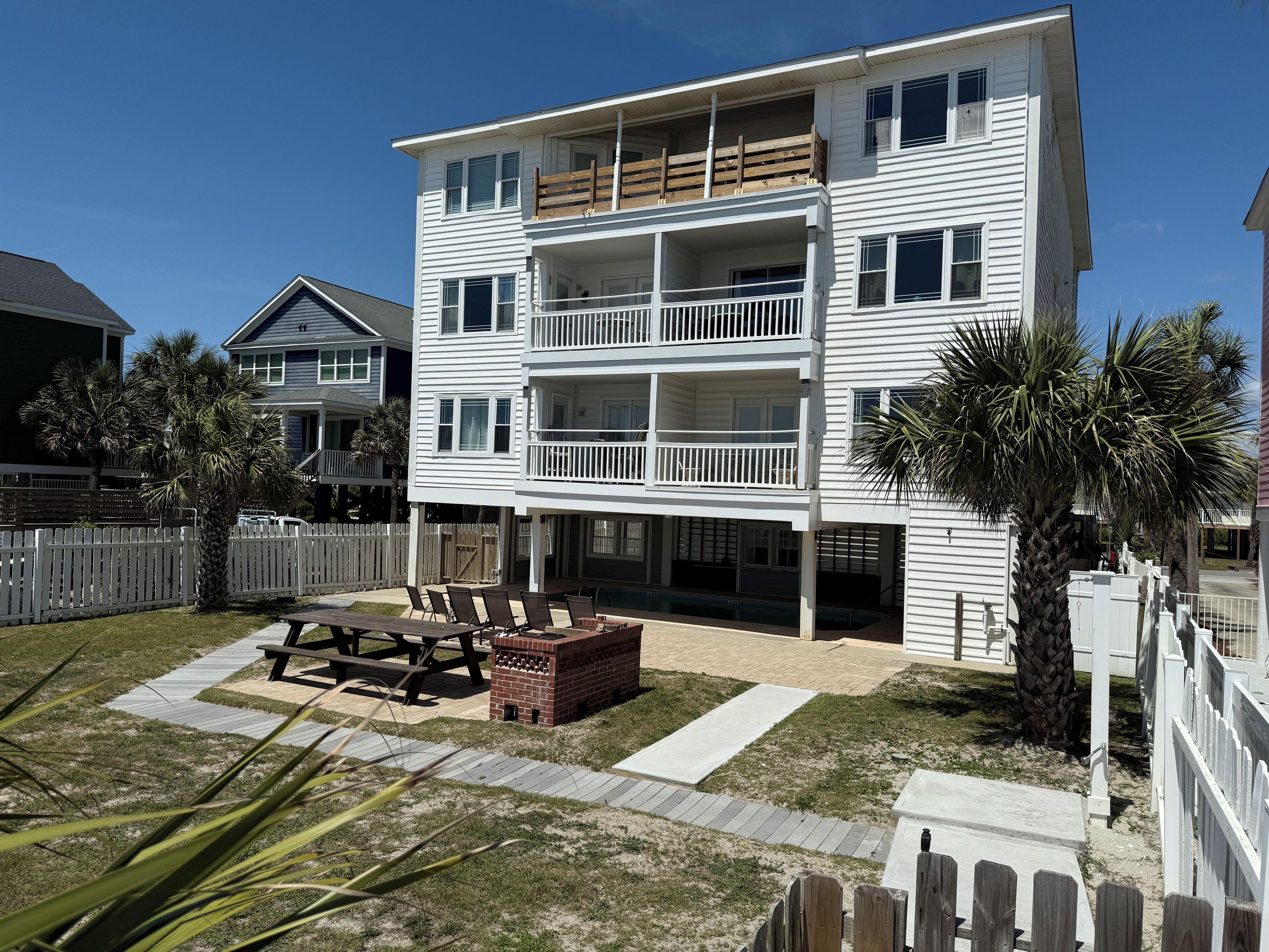 A multi-story residential building with a balcony, a patio with a barbecue, and a pool area.