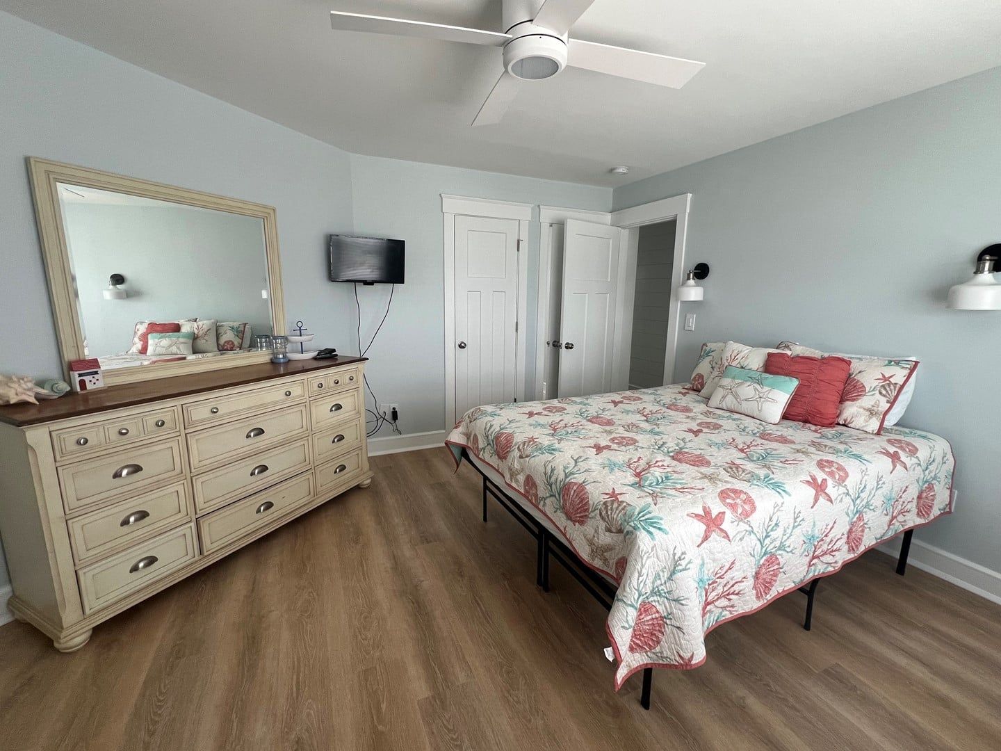 Une chambre à coucher comprenant un lit, une commode, un téléviseur et un ventilateur de plafond.