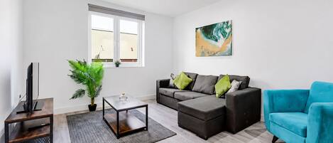 A modern living room with a sofa, a coffee table, a TV, and a plant.