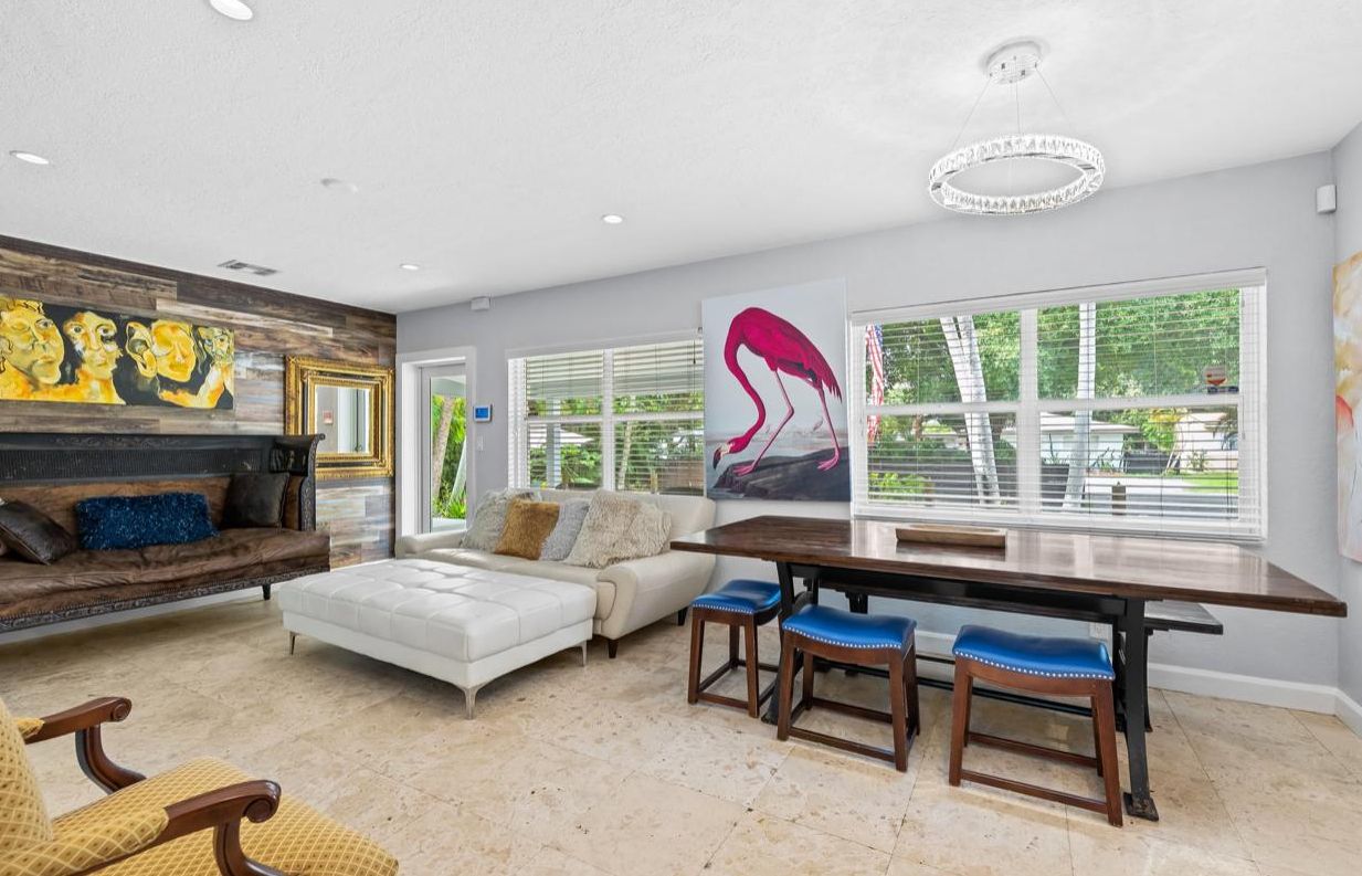 A modern living room with a sofa, a dining table with chairs, and artwork on the walls.