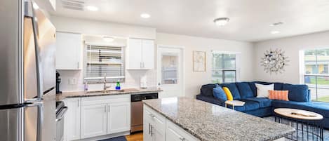 A modern kitchen with white cabinets, granite countertops, and stainless steel appliances.