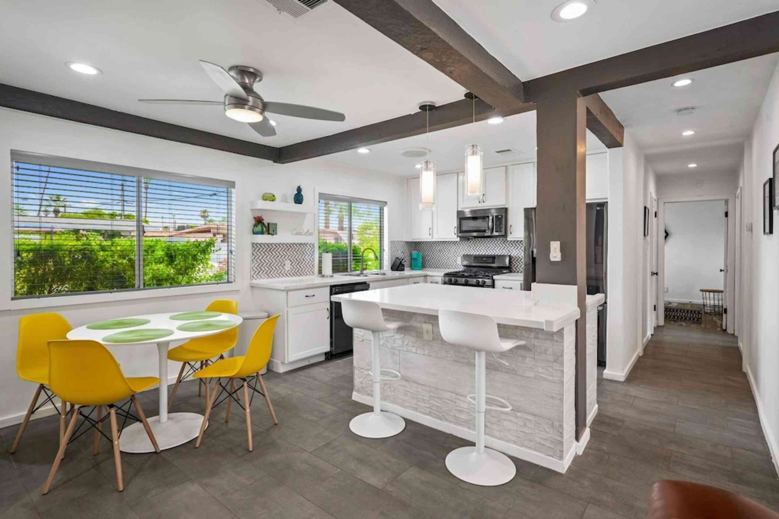 Una cocina moderna con barra, sillas amarillas y vistas al verdor exterior.