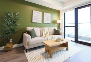 A living room with a sofa, a coffee table, a lamp, and a large window. - Casa Verde | Skyline Views Near Square One (Mississauga)