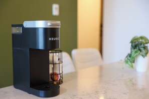 A Keurig coffee maker on a marble countertop with a plant in the background.