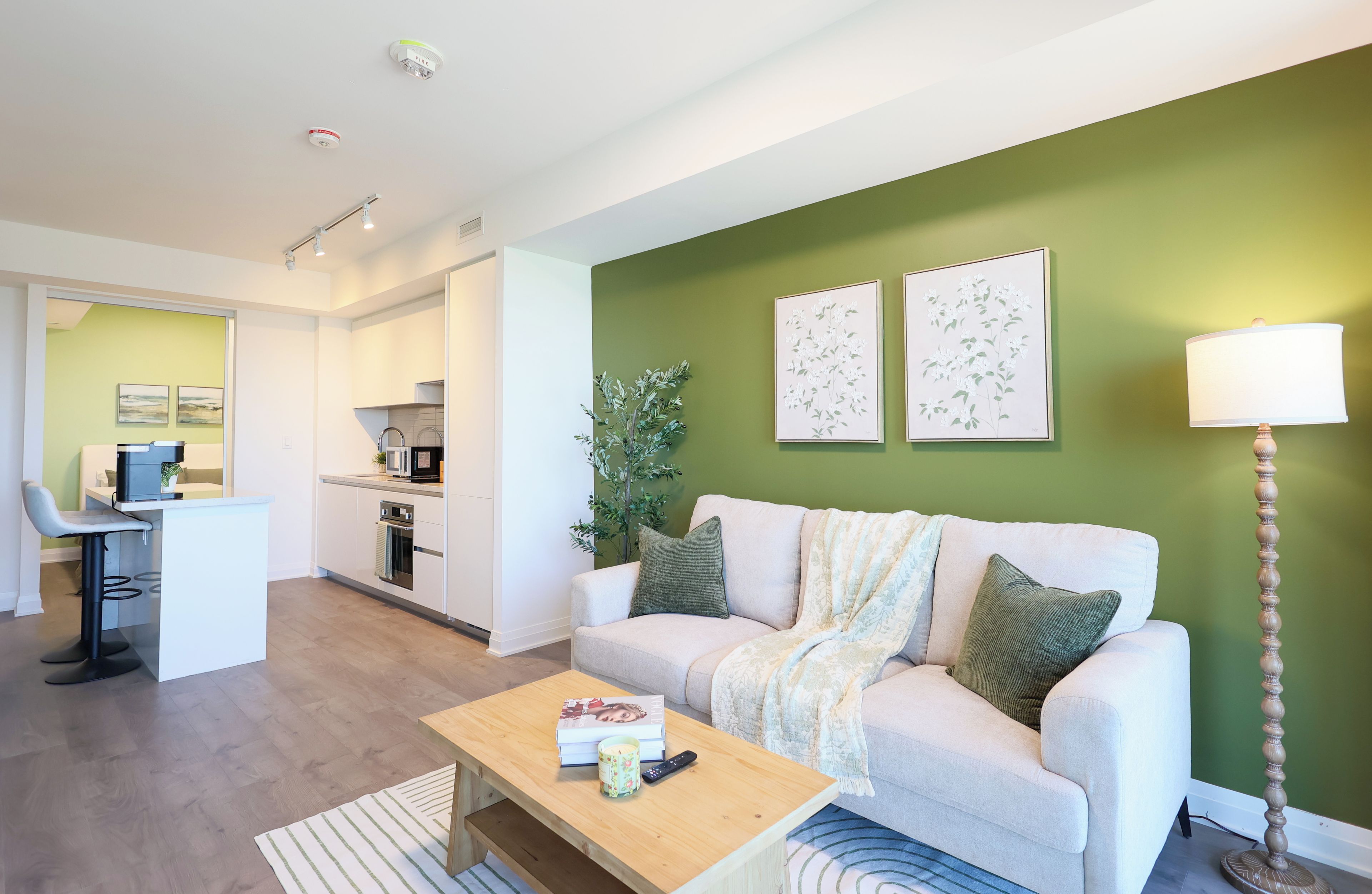 Un salon moderne avec un canapé, une table basse et un coin repas, la cuisine étant visible à l’arrière-plan.