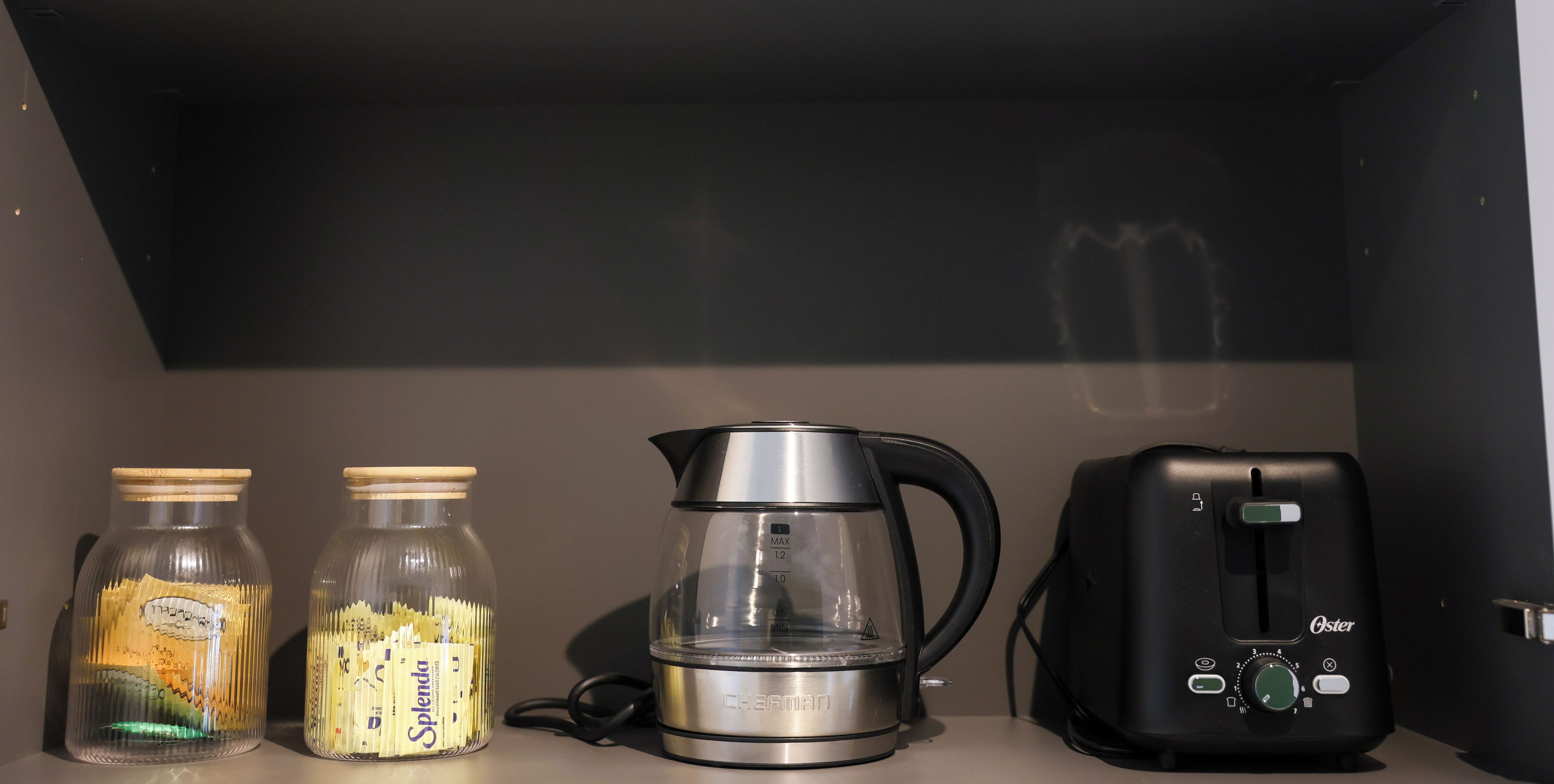 Eine Küchenarbeitsfläche mit einer Kaffeemaschine, zwei Gläsern mit Etiketten und einem Toaster.
