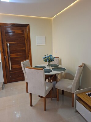 A dining area with a round table, four chairs, a vase with flowers, and a wooden door. - Residencial canto dos passarinhos (Alto Paraíso de Goiás)