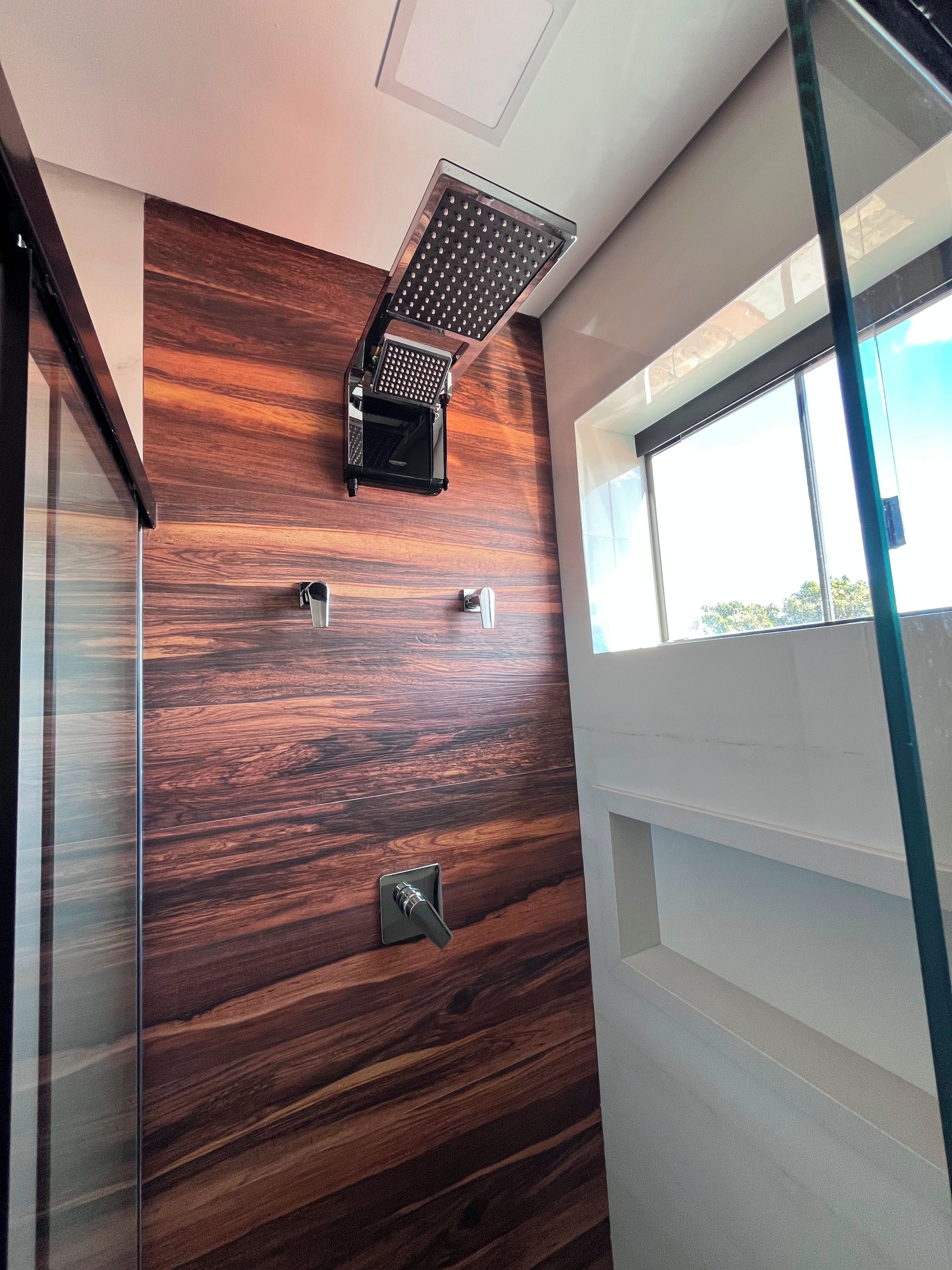 A modern bathroom with a wooden wall, a shower head, and a window.