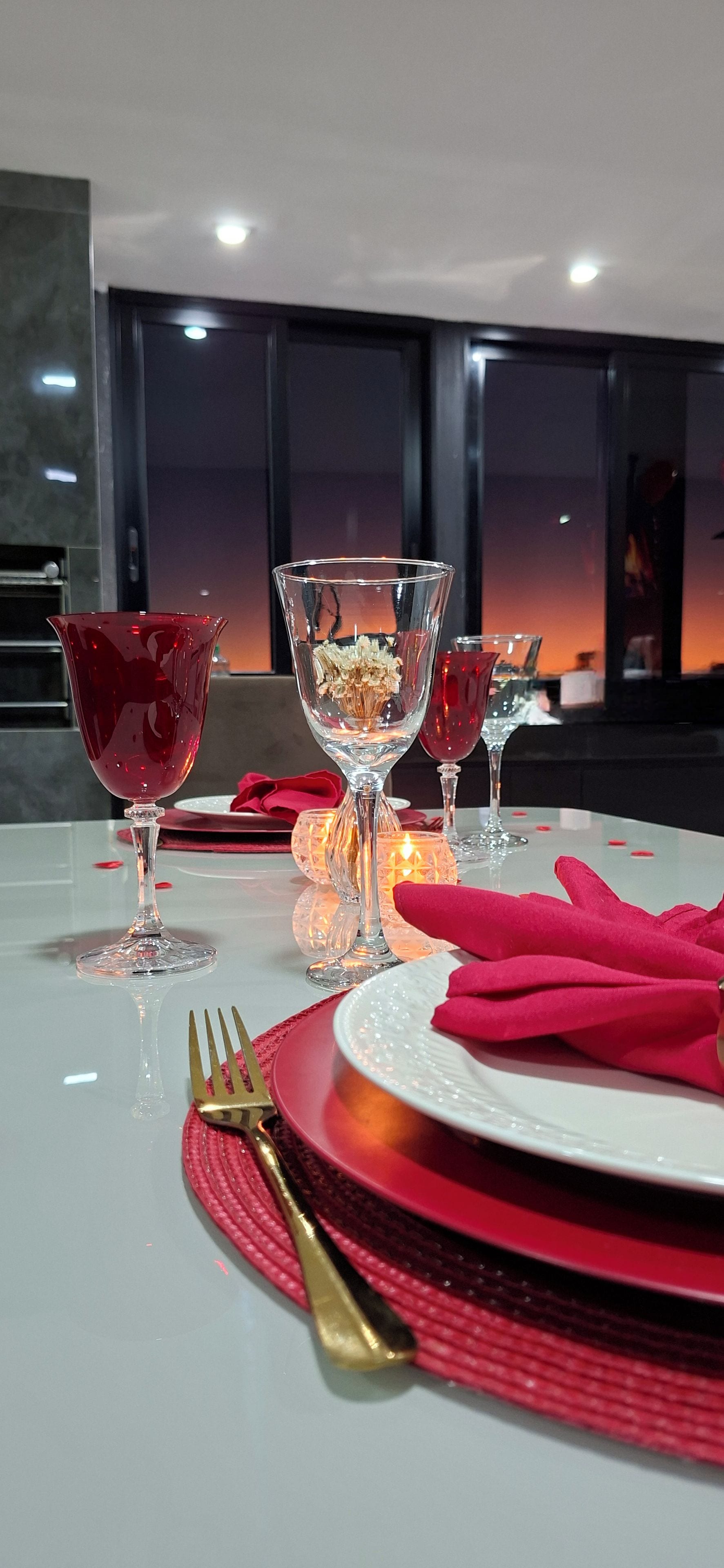 A table set for dining with a glass vase, candles, and red napkins.