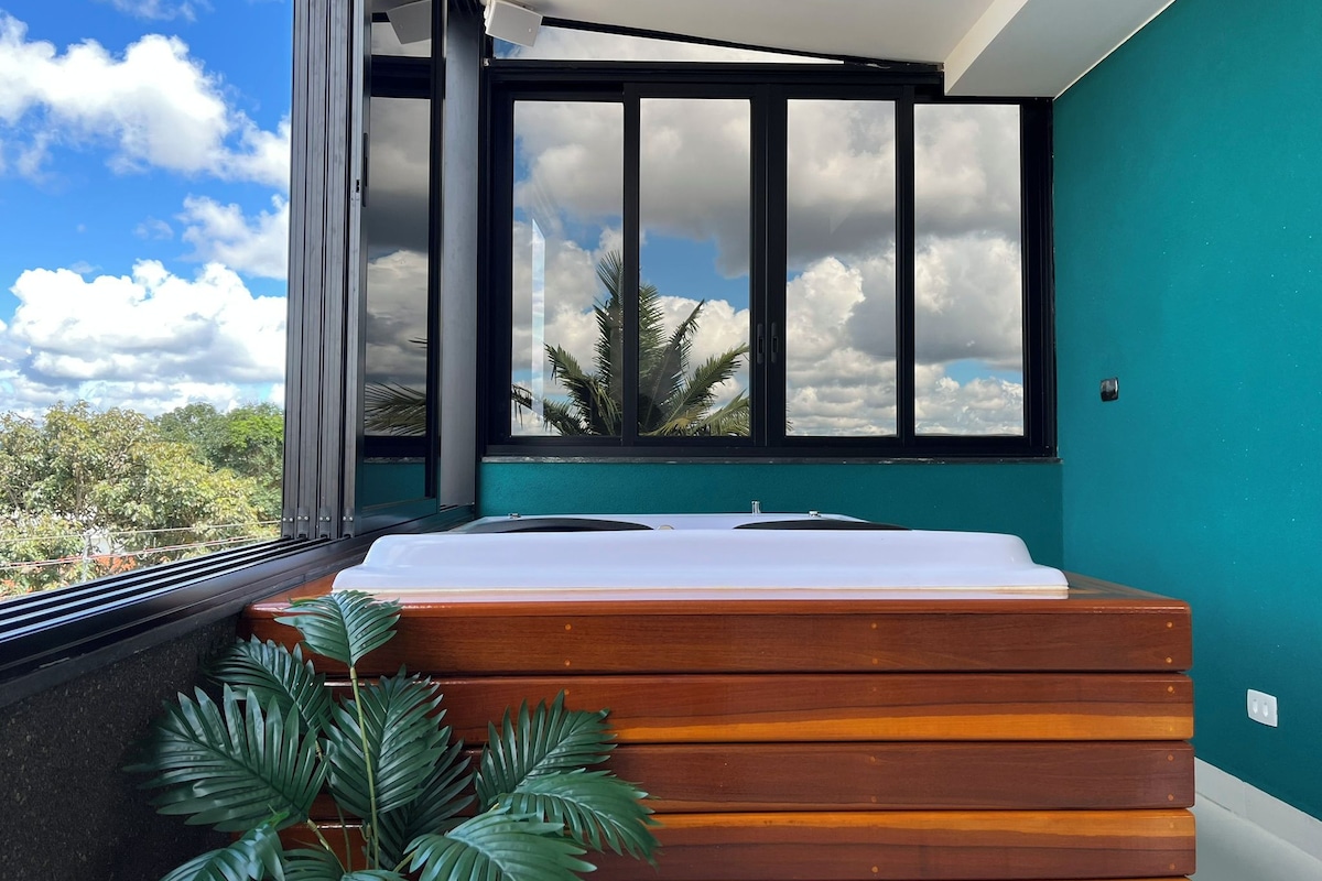 A modern room with a large window, a wooden platform, and a view of the sky and clouds.
