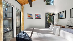 Une chambre à coucher avec un lit, une fenêtre et deux œuvres d’art encadrées accrochées au mur.