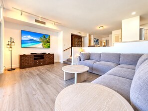A modern living room with a grey sofa, a coffee table, and a flat-screen TV mounted on the wall. - Kaanapali Royal | Ocean View 4 BR, Sleeps 13 | Car Incl. w/ 6+ Nights | KRO ML-3791 by KBM (Lahaina)