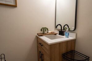 Une salle de bain avec un lavabo blanc, un meuble en bois et un miroir.
