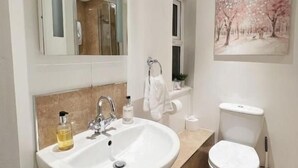 A bathroom with a sink, toilet, and a painting on the wall. - Ellie's Guest House (Whitby)