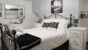 A bedroom with a bed, bedside tables, a mirror, and a ceiling light fixture. - Ellie's Guest House (Whitby)